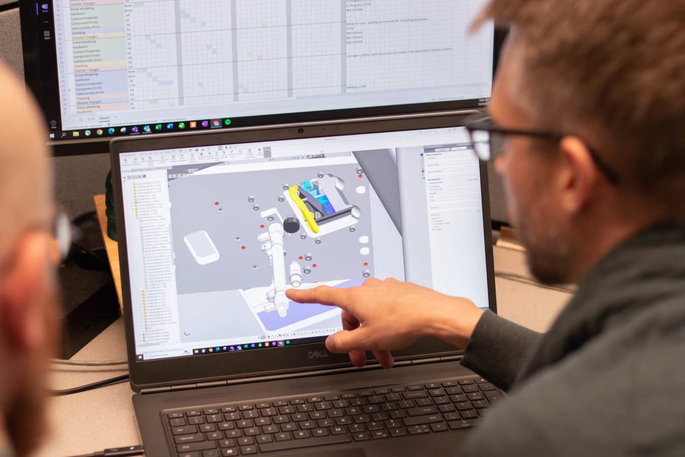 Machine Designer pointing to design on computer