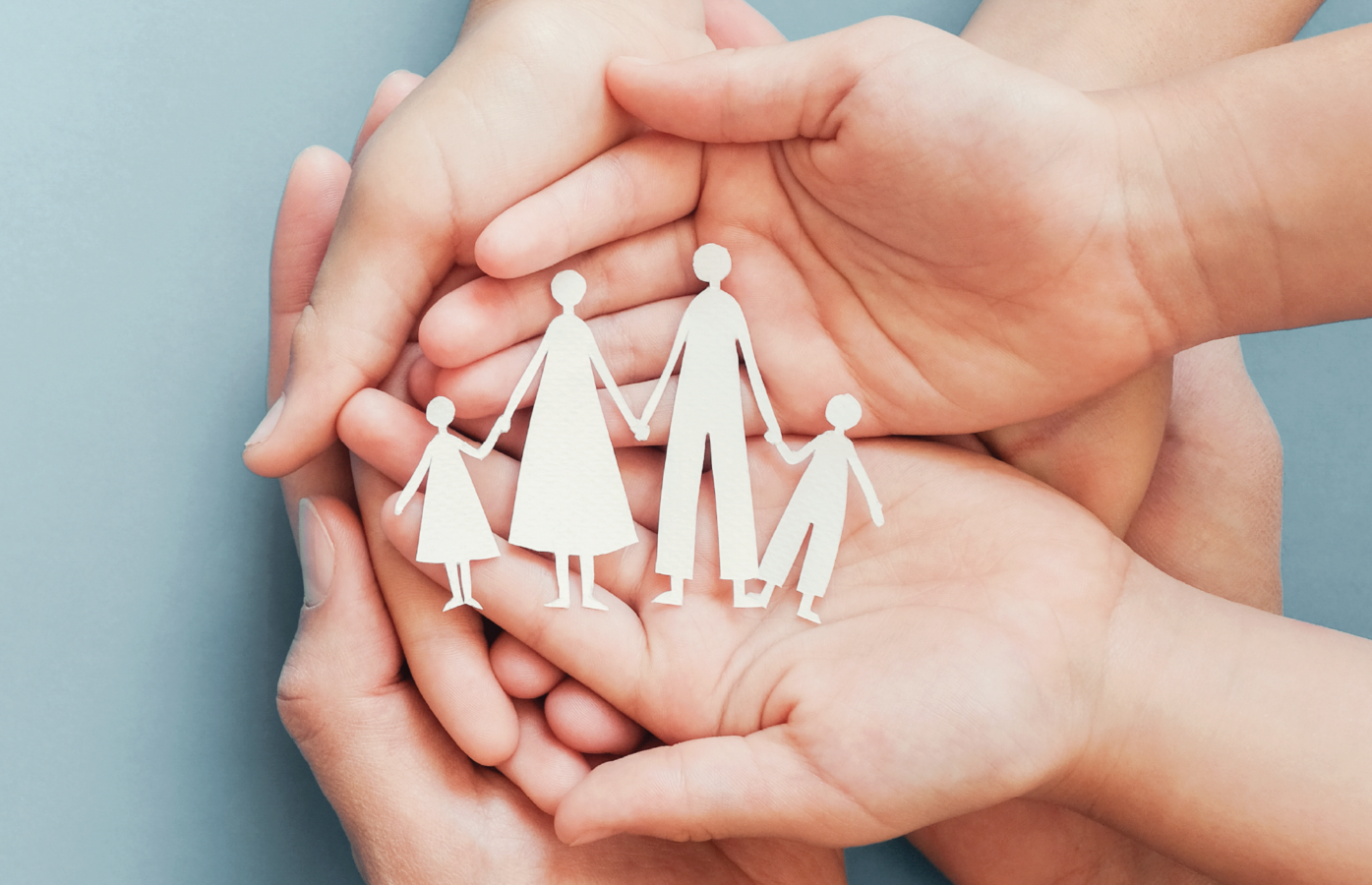 A parents hands and child's hands old a paper cut out of a family