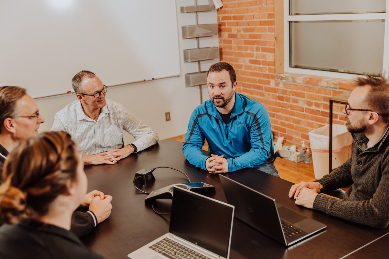 Engineers sit around a table discussing a project with a customer